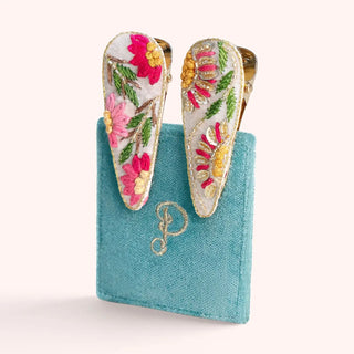 Floral earrings on a blue card with a logo