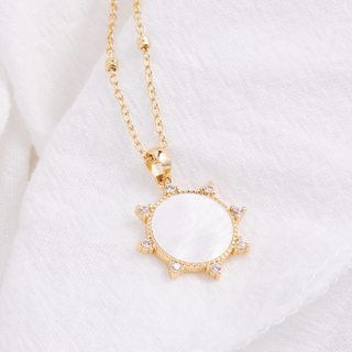 Gold necklace with a circular pendant on a white background