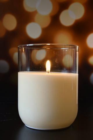 Candle in a glass container with a blurred warm background