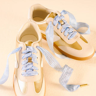 Beige sneakers with blue checkered laces on a beige background
