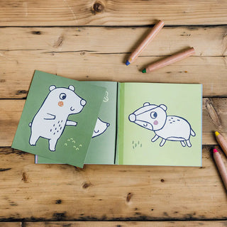 Children's coloring book with animal illustrations on a wooden surface with crayons.