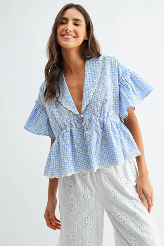 Woman wearing a blue checkered blouse with ruffled details on a white background