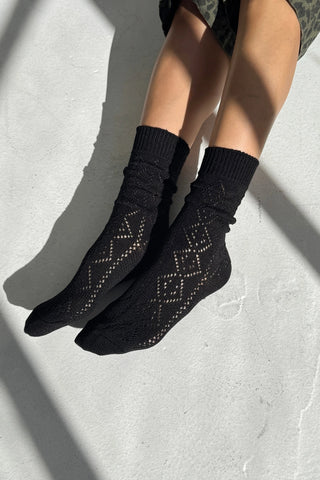Black patterned socks worn by a person on a light gray background
