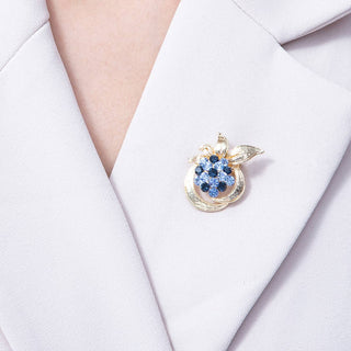 Gold brooch with blue gemstones on a white blazer