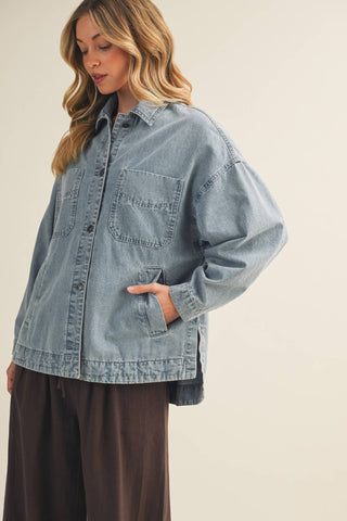 Woman wearing a light blue denim jacket on a beige background