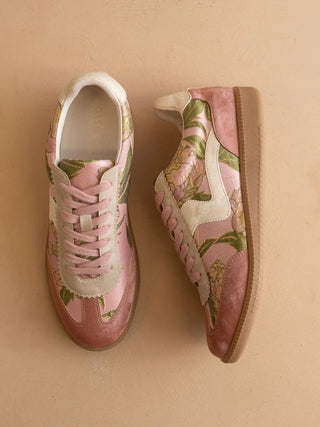 Pair of pink floral sneakers on a beige background