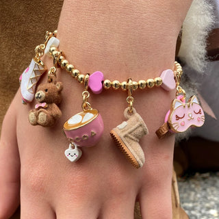 Bracelet with various charms including a teddy bear, ice cream, and cat on a wrist.