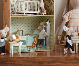 Miniature dollhouse scene with toy mice and furniture on a wooden floor.
