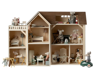 Wooden dollhouse with detailed interior and furniture on a white background