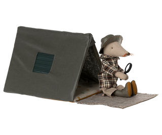 Stuffed animal mouse in a plaid outfit with a hat and boots, sitting next to a small tent on a white background.