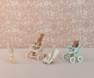 Wooden toy figures of bunnies with strollers on a floral background