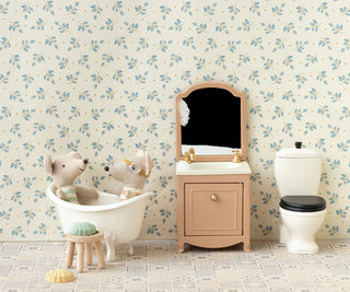Bathroom setting with a vanity, toilet, and decorative wall paper.