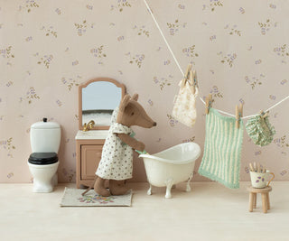 Miniature bathroom scene with a bear character in a bathrobe, bathtub, and floral wallpaper.
