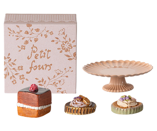 Decorative cake stand with miniature cakes and a 'Petit fours' box on a white background