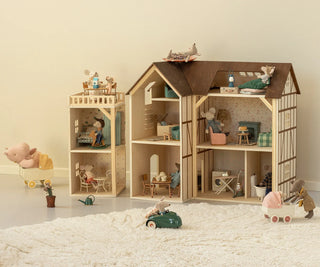 Wooden dollhouse with miniature furniture and accessories on a light surface.