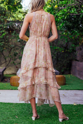 Woman wearing a floral dress standing outdoors with greenery in the background