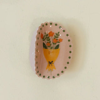 Decorative hair clip with floral design on a light pink background