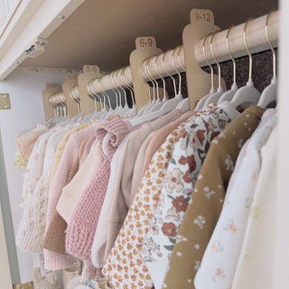 Children's clothing on hangers with size labels in a closet.