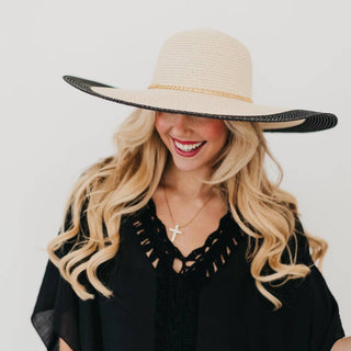 Woman wearing a wide-brimmed straw hat with black band on a white background