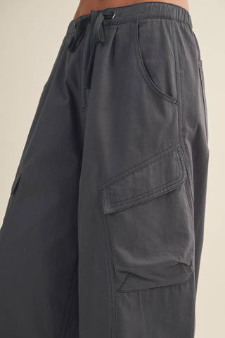 Dark gray cargo pants on a beige background