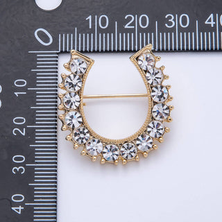 Gold and crystal brooch next to a ruler for size reference
