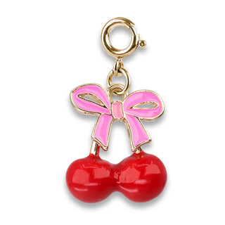A cherry charm with a gold-tone clasp, featuring two glossy red cherries and a pink bow with gold-tone outlines, set against a plain white background.