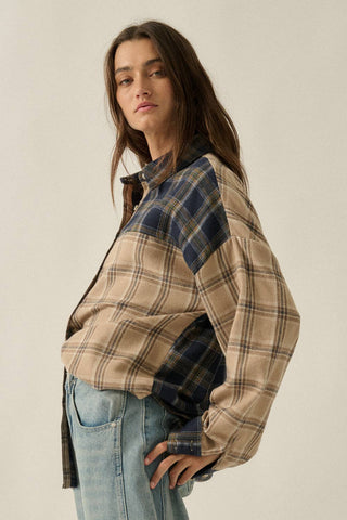 Woman wearing a plaid shirt over a black top with light blue jeans on a beige background