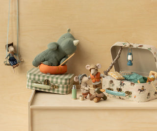 Toy elephant on a suitcase with other toys on a wooden shelf
