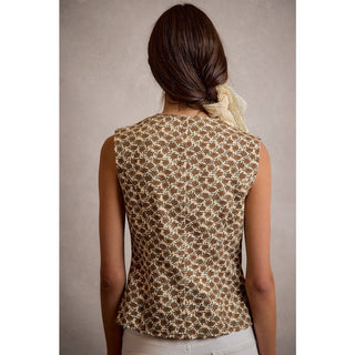 Woman wearing a sleeveless patterned top against a neutral background