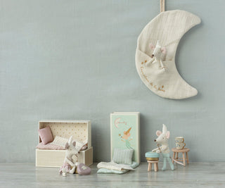 Children's room with toys, a moon-shaped hanging decoration, and a small bed.