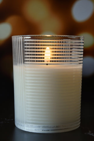 Candle in a ribbed glass holder with a blurred bokeh background
