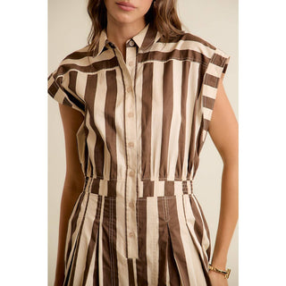 Woman wearing a sleeveless brown and beige striped dress against a neutral background