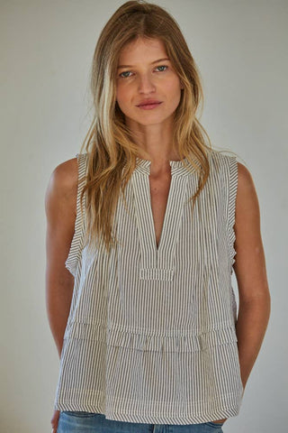 Woman wearing a sleeveless striped shirt against a plain background
