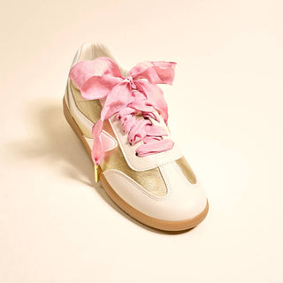 White sneaker with pink laces on a beige background