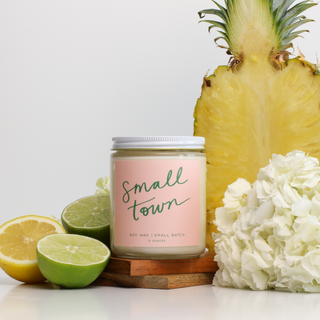 Candle labeled 'Small Town' with a pineapple, lemon, lime, and flowers on a white background