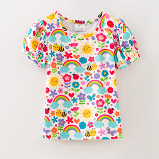 Children's t-shirt with colorful rainbow, flower, and bee pattern on a white background