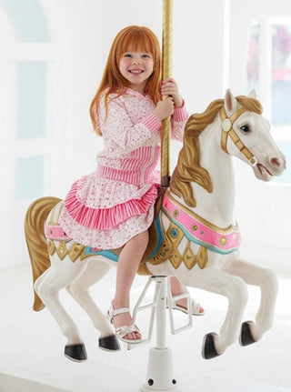 Child in a pink dress sitting on a carousel horse