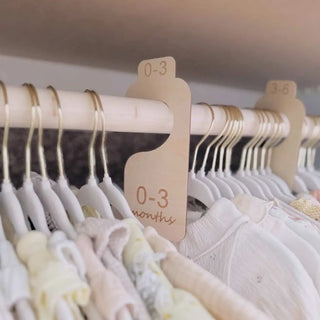 Baby clothes on hangers with size tags on a rack