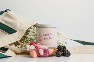 Candle labeled 'Farmers Market' with decorative elements on a white background