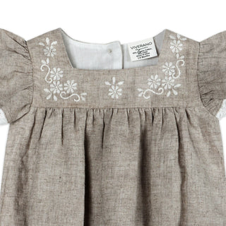 Baby dress with floral embroidery and 'Viverano' label on a white background