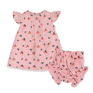 Pink baby dress with cherry pattern and matching bloomers on a white background