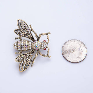 Decorative bee brooch with gemstones next to a quarter for scale on a white background