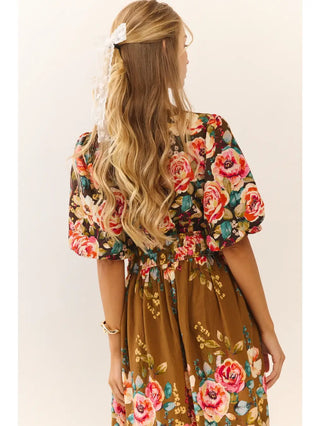 Woman wearing a floral dress with puff sleeves on a beige background