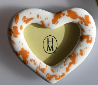 Heart-shaped frame with gold center and orange and white pattern on a ivory background