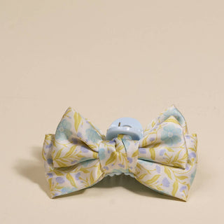 Floral patterned bow tie with a blue clip on a beige background