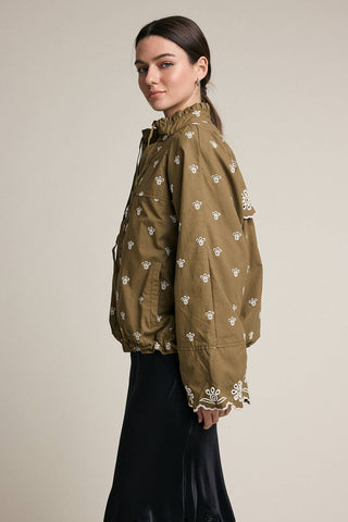 Woman wearing a green patterned shirt against a beige background