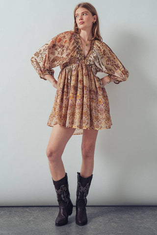 Woman wearing a floral dress and black boots against a plain background