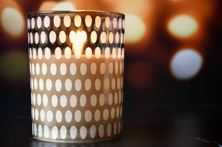 Candle in a decorative holder with a polka dot pattern on a blurred background