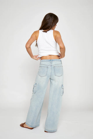 Woman wearing light blue jeans and a white top on a plain background
