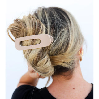 Person with blonde hair tied up with a beige hair clip on a white background